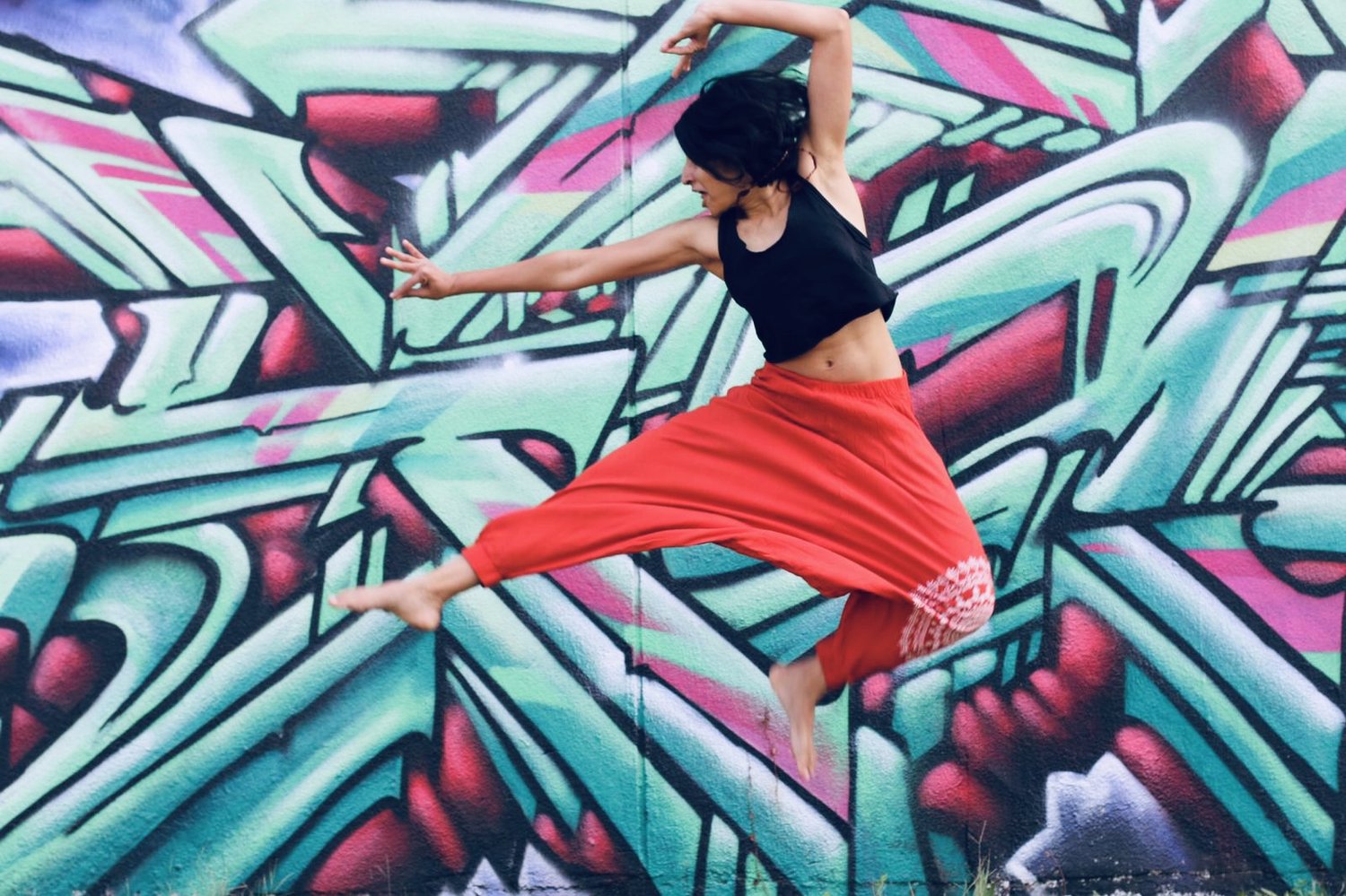 Dancer leaping in front of a mural
